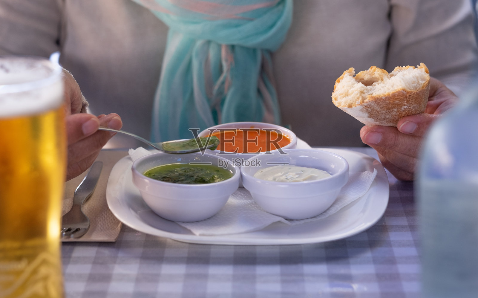 关注一个白人妇女的手在餐厅的桌子上享受食物品尝三种典型的加那利群岛的酱料，被称为“mojo”照片摄影图片