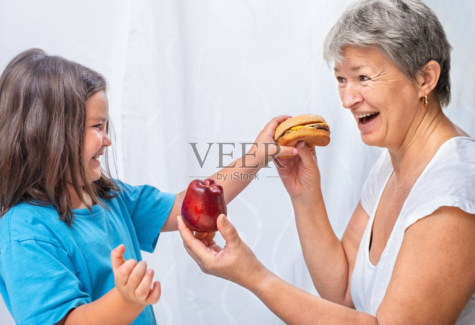 祖母给她的孩子一个苹果，而不是一个汉堡照片摄影图片