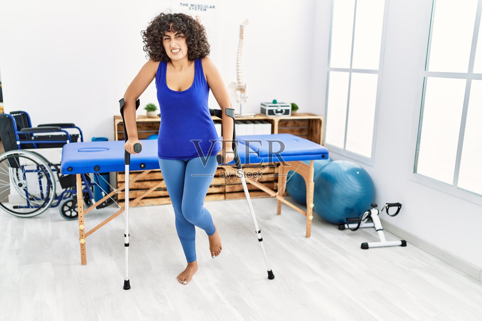 年轻的中东妇女在诊所用拐杖走路照片摄影图片