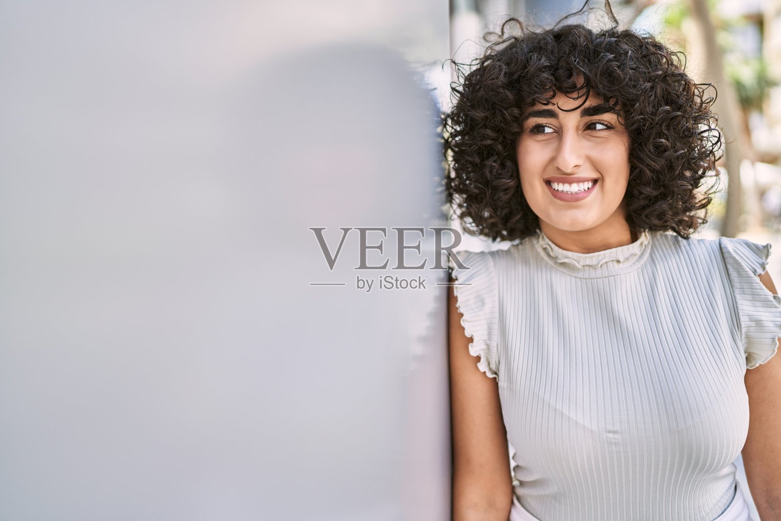 年轻的中东妇女微笑着快乐地站在城市。照片摄影图片