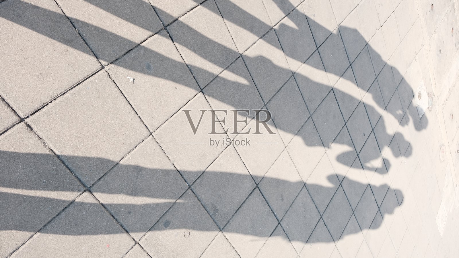 三个人的影子在人行道上。照片摄影图片