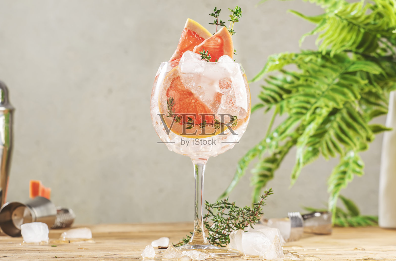 金汤力是一款新潮的酒精鸡尾酒，配以干金汤力、苦金汤力、柠檬汁、葡萄柚、百里香和冰，配以酒吧工具。木制桌子背景与复制空间照片摄影图片