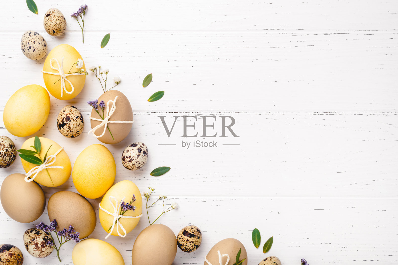 白色的桌子上放着复活节彩蛋和鲜花。照片摄影图片