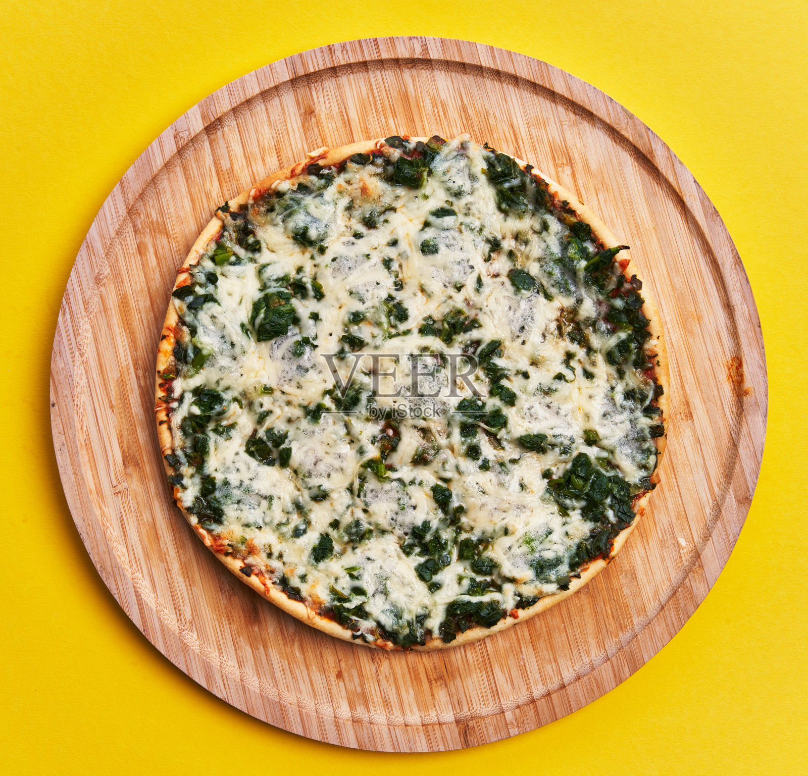 单菠菜意大利披萨在黄色背景的木制盘子照片摄影图片