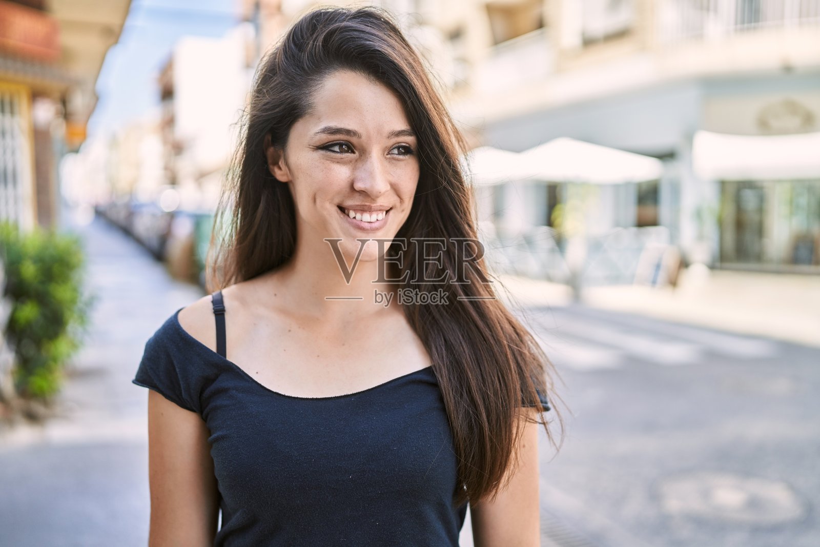 年轻的西班牙女孩微笑着快乐的站在城市。照片摄影图片