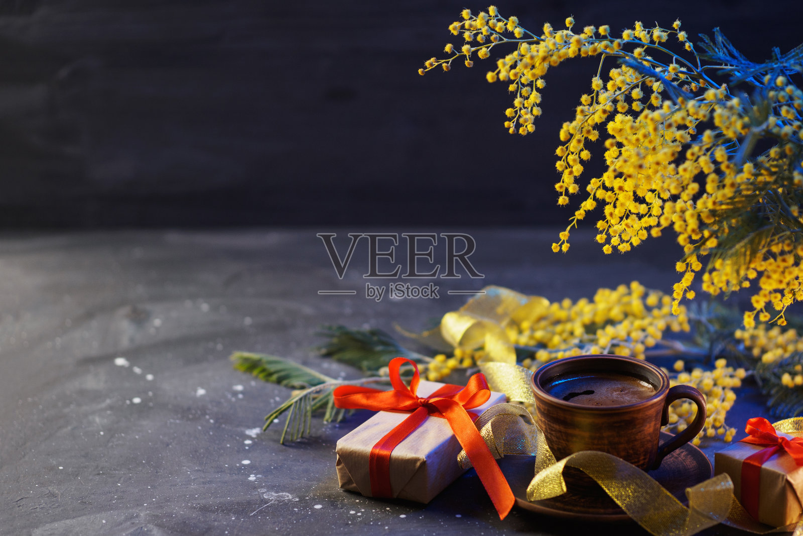 桌上有一杯咖啡和一束黄色的含羞草花。礼品盒和复印空间照片摄影图片