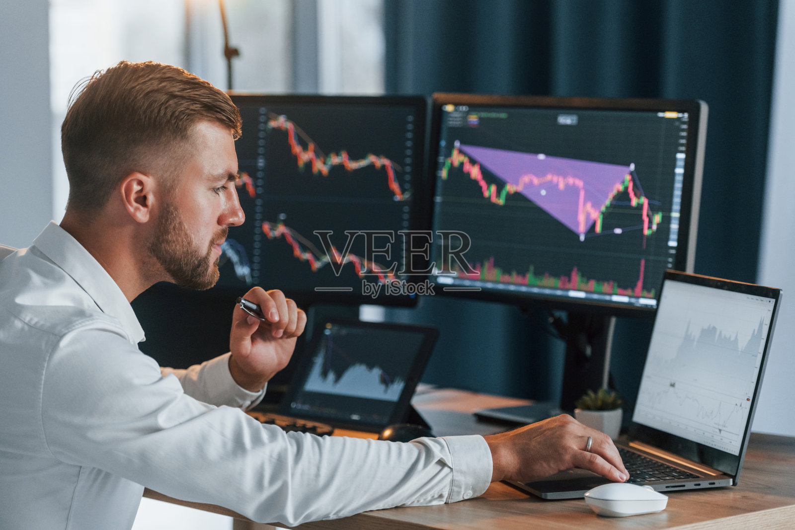 穿着正装的年轻成功商人的办公室里有多个屏幕照片摄影图片