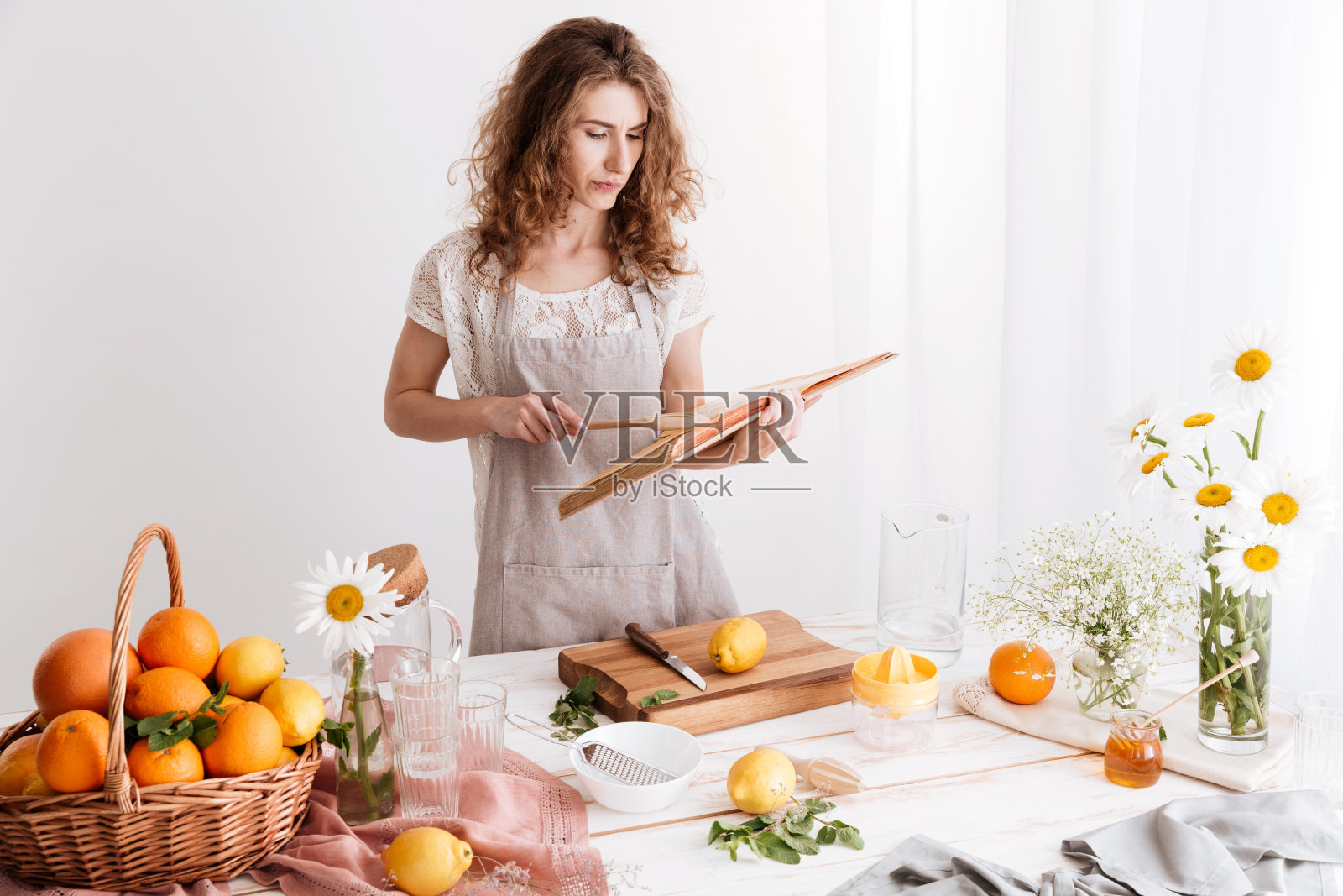 一个女人站在室内，旁边的桌子上放着很多柑橘照片摄影图片