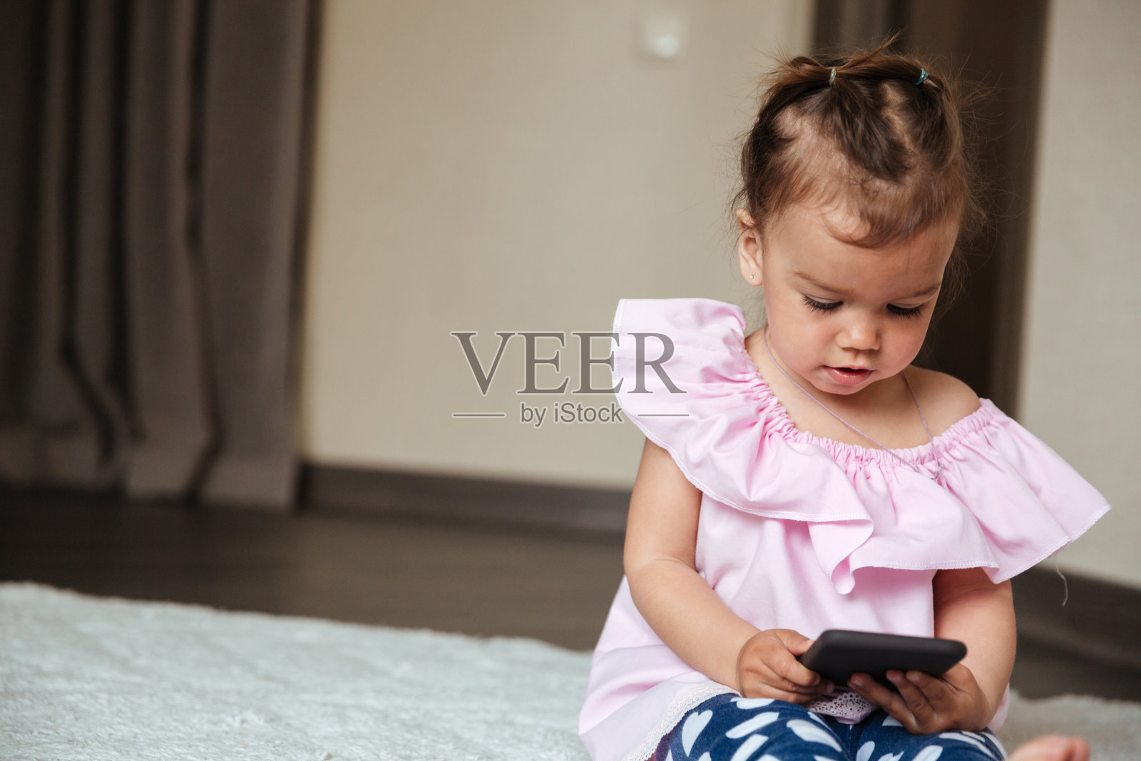 专心的小女孩坐在床上用手机照片摄影图片