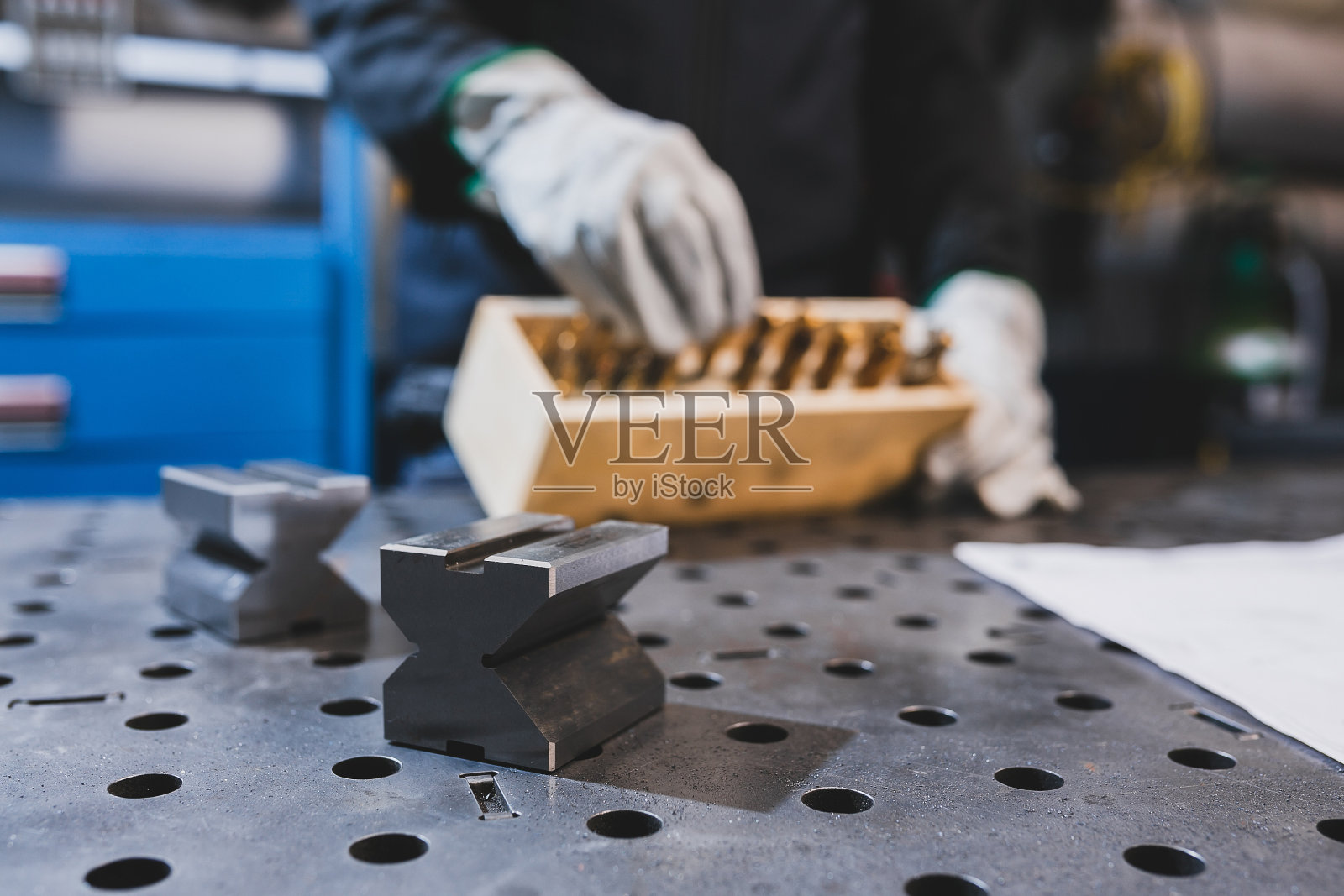 工人带防护手套的手拿着装有钻头的盒子照片摄影图片