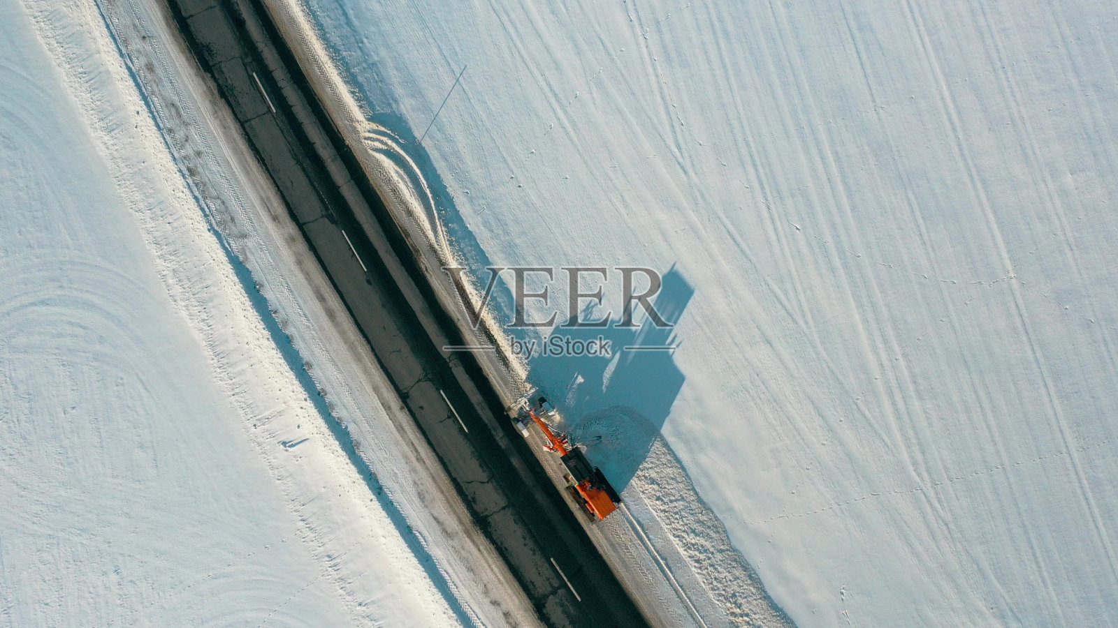 鸟瞰图，除雪拖拉机清除道路积雪。在阳光明媚的冬日鸟瞰道路照片摄影图片