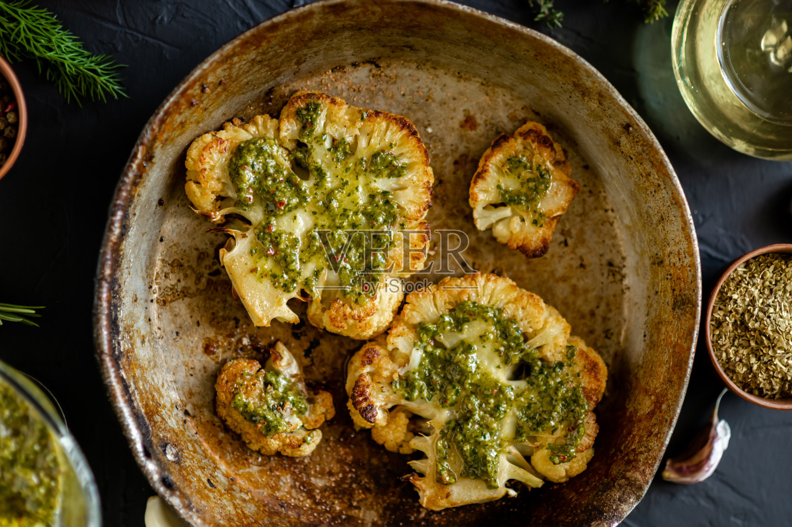 花椰菜牛排加香料放在煎锅里。橄榄油，墨西哥辣酱，香草，各种香料。黑暗的背景。素食。照片摄影图片