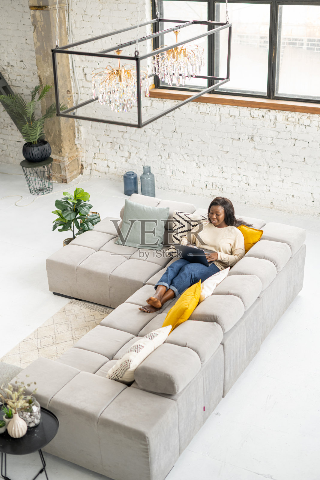 放松的多种族女子坐在沙发上，用笔记本电脑上网聊天，回复电子邮件。一个快乐的女人在网络上消磨闲暇时间照片摄影图片