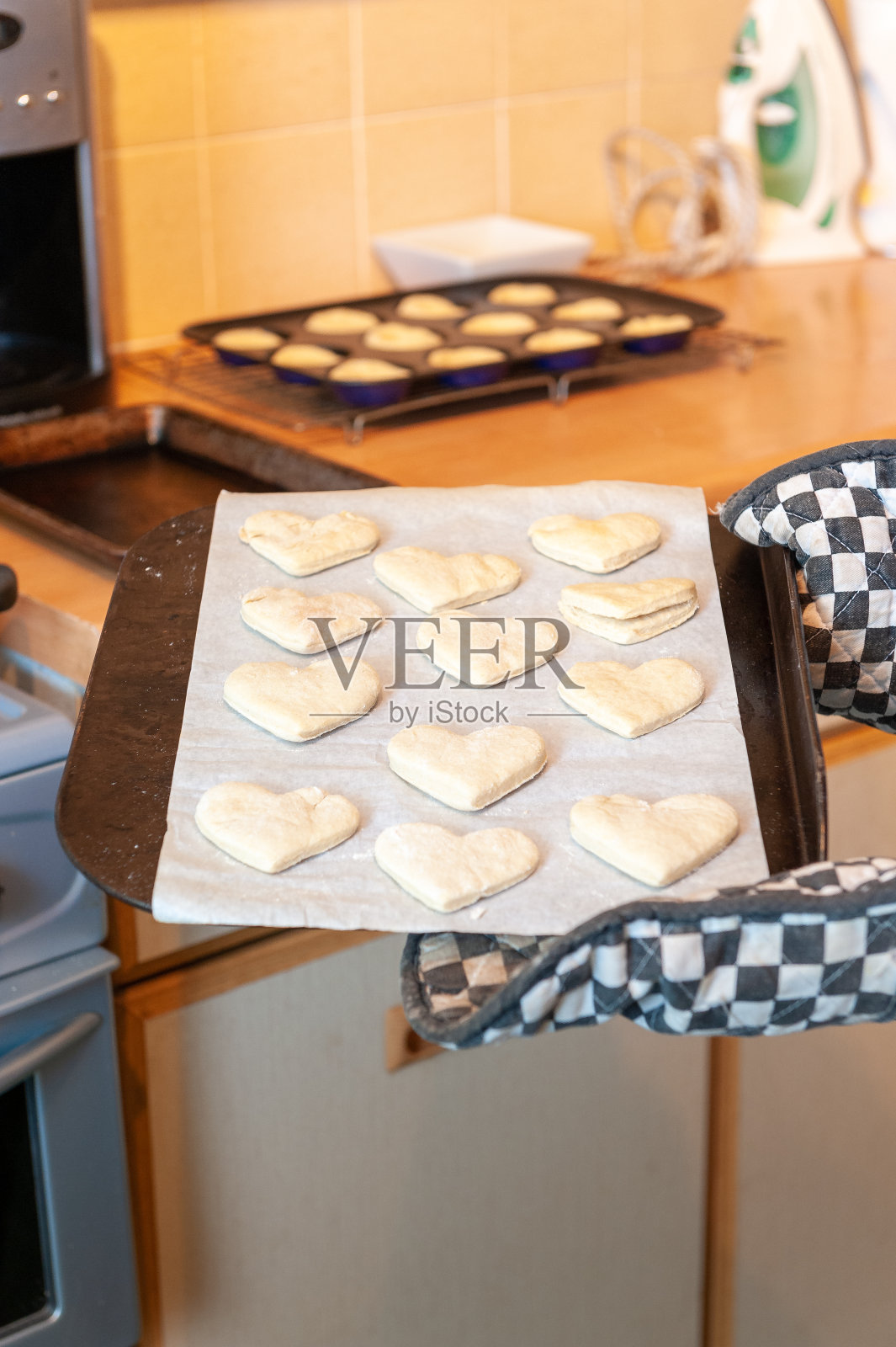 一个心形的烤盘，用黑白烤箱手套托着照片摄影图片