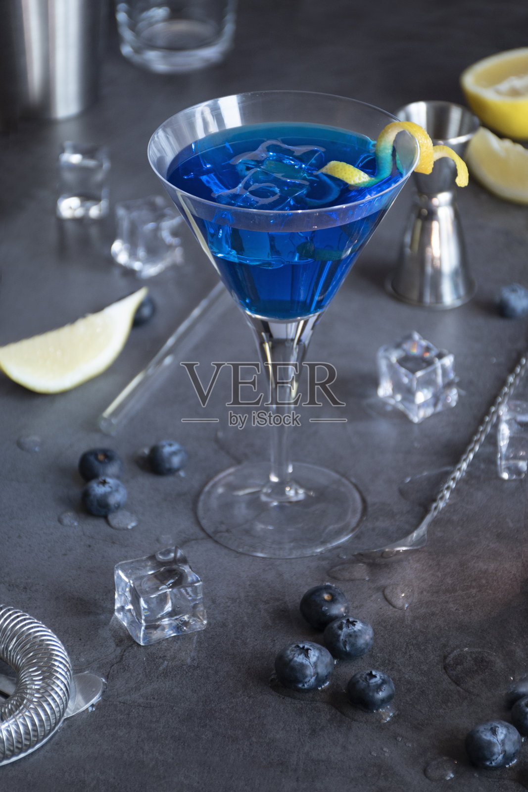 蓝泻湖鸡尾酒，配蓝柑甜酒、伏特加、柠檬汁、蓝莓和苏打水。蓝色鸡尾酒马提尼杯，黑色背景。照片摄影图片