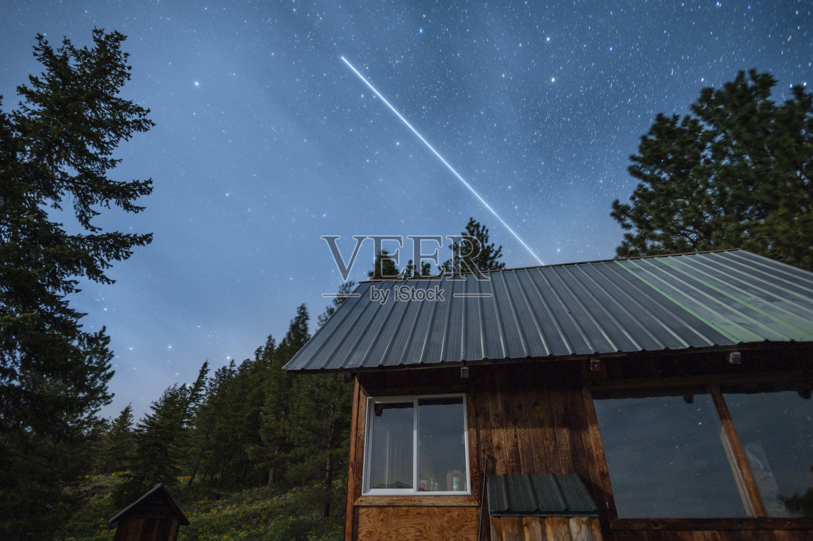 晚上，国际空间站在一个小木屋上空飞行照片摄影图片
