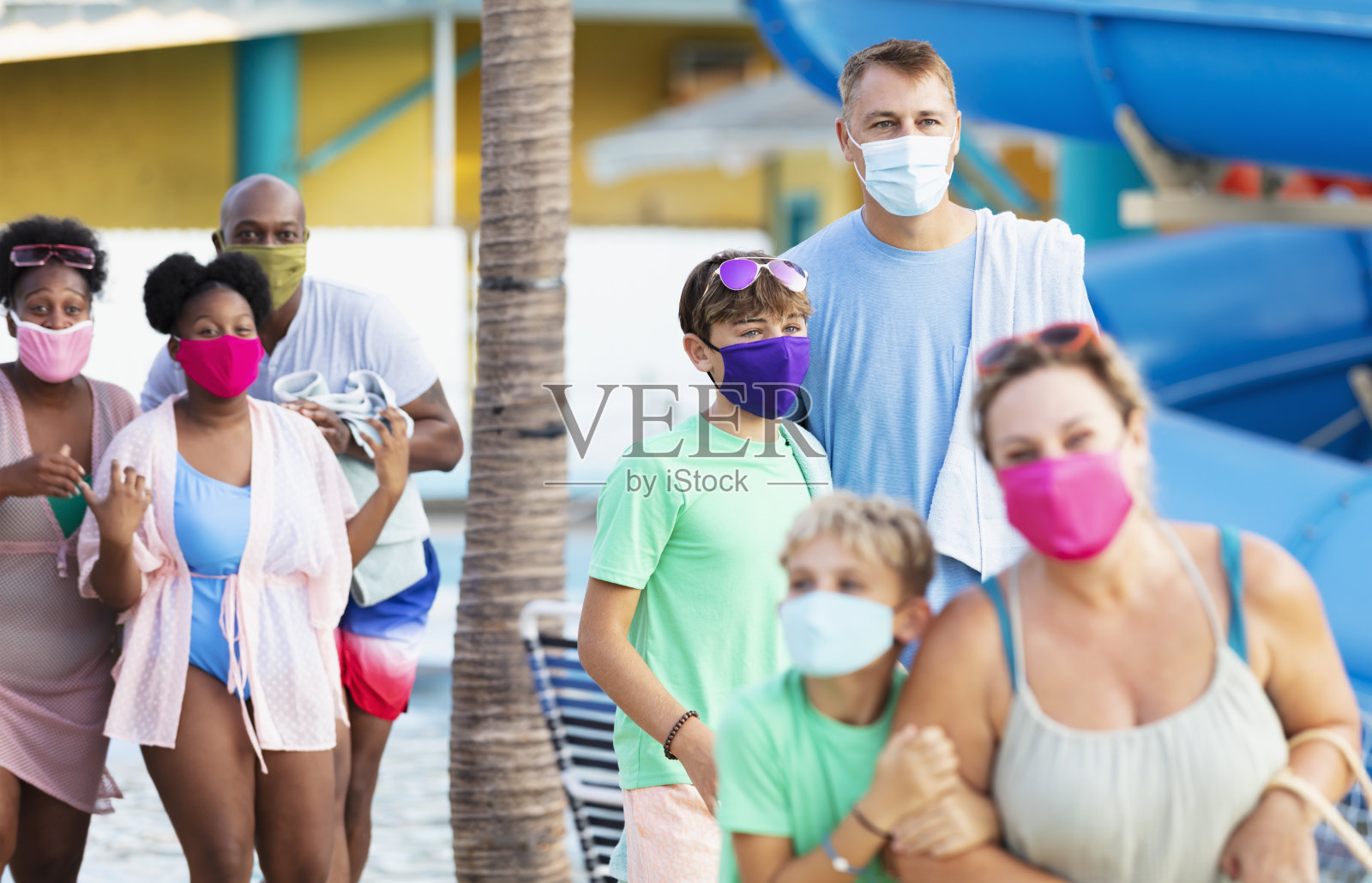 两个多种族家庭在水上公园，戴着口罩照片摄影图片