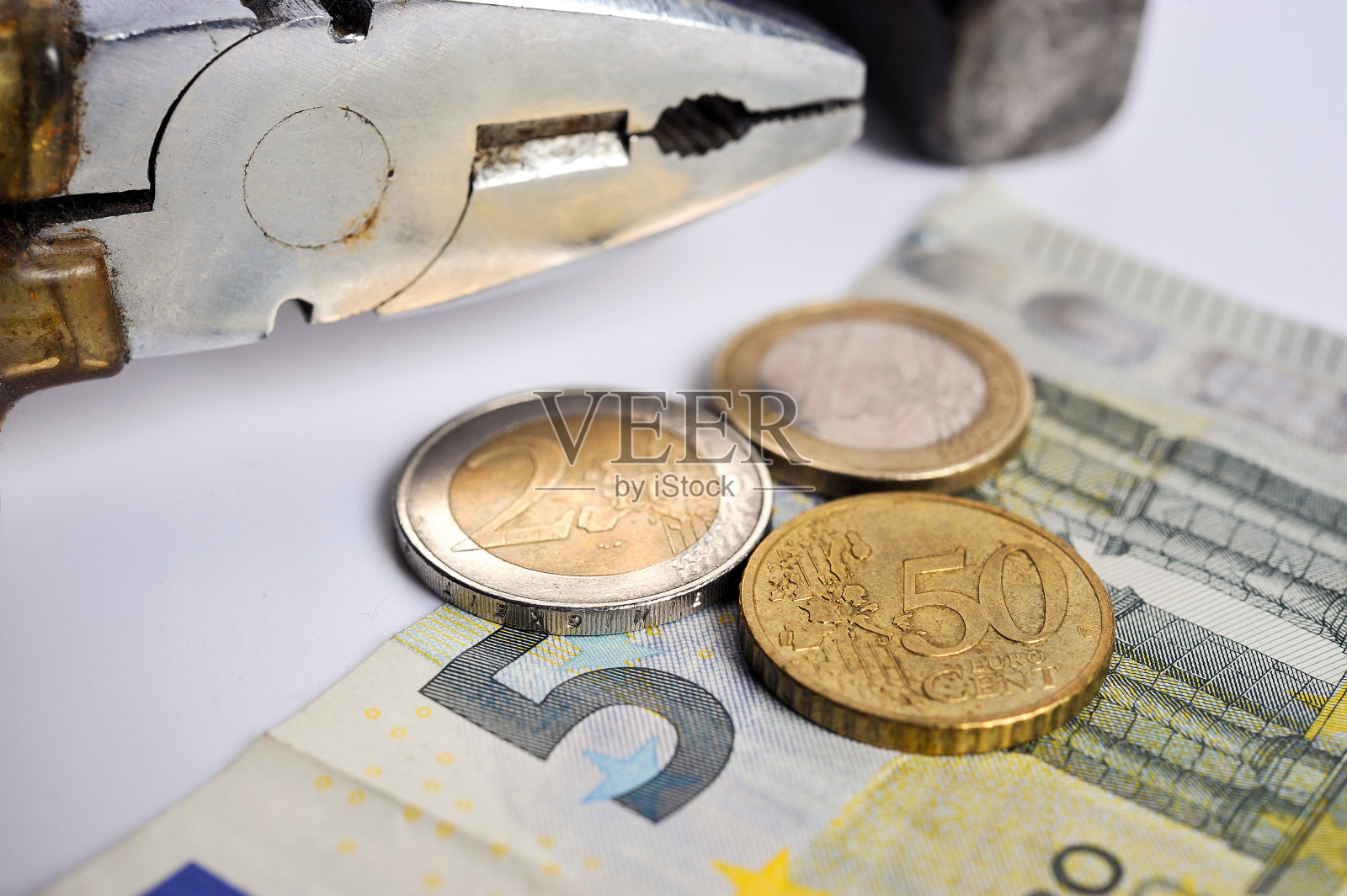 概念工资和薪水:欧元纸币上的欧元硬币，背景是一把钳子和一把锤子照片摄影图片
