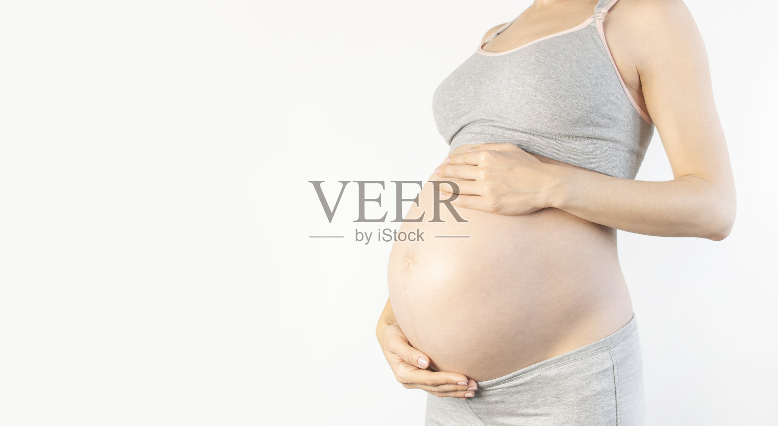 美丽的年轻孕妇手放在她的腹部白色背景。对孩子，怀孕和母亲的期望的概念。孕妇的温柔照片。特写，文字的位置照片摄影图片