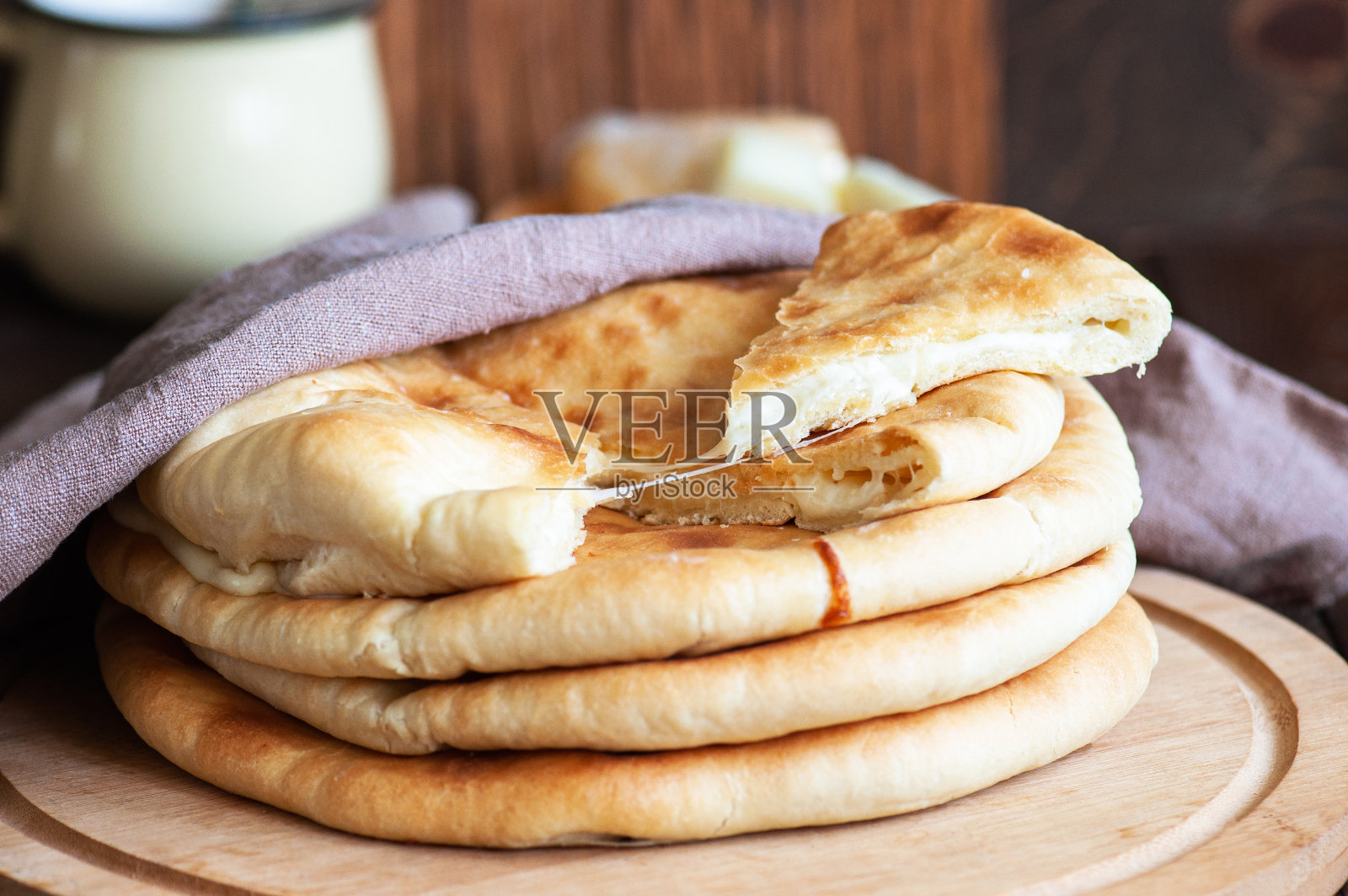 广受欢迎的Osetian哈切布里派，里面塞满了土豆和奶酪，整块或切片放在木板上，木质背景。照片摄影图片