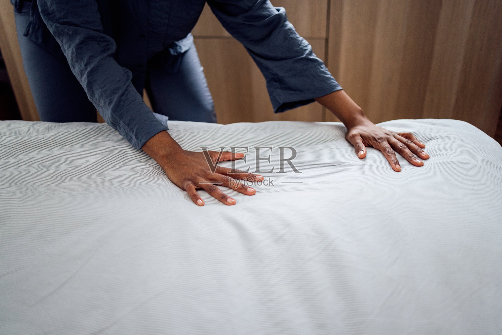 匿名的女人在早上铺床照片摄影图片