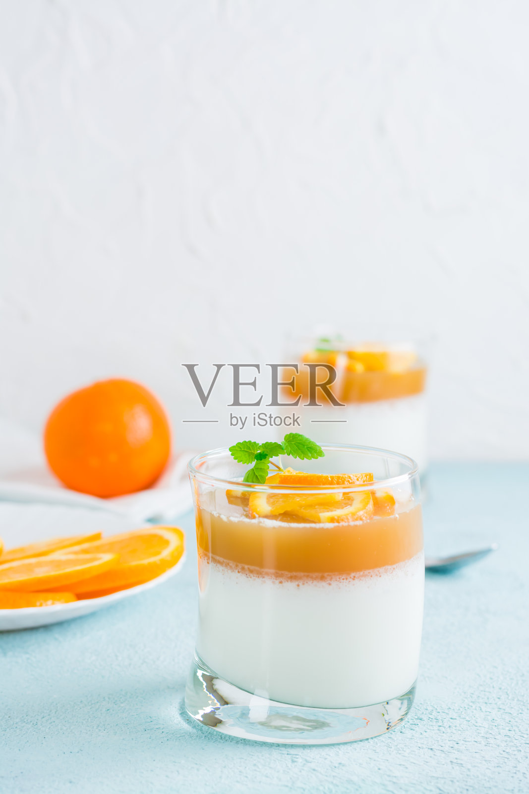 淡色的桌子上放着盛着橘色和薄荷叶的玻璃杯。甜蜜的意大利甜点。俯视图照片摄影图片
