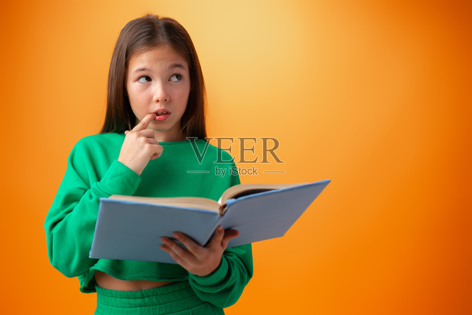 聪明的少女的肖像与书的橙色背景照片摄影图片