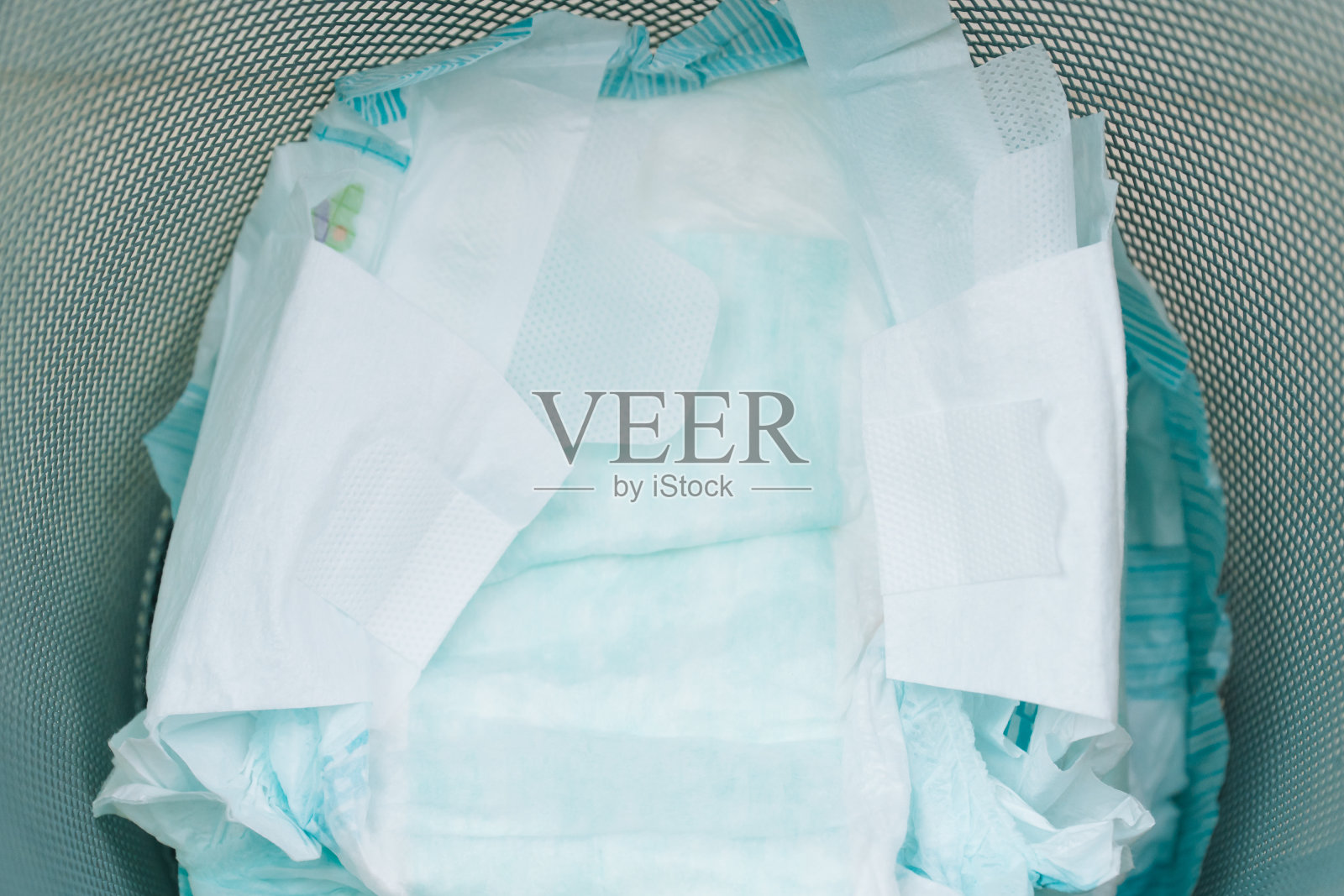 把用过的尿布扔进垃圾桶。幼儿保育概念。环境污染照片摄影图片