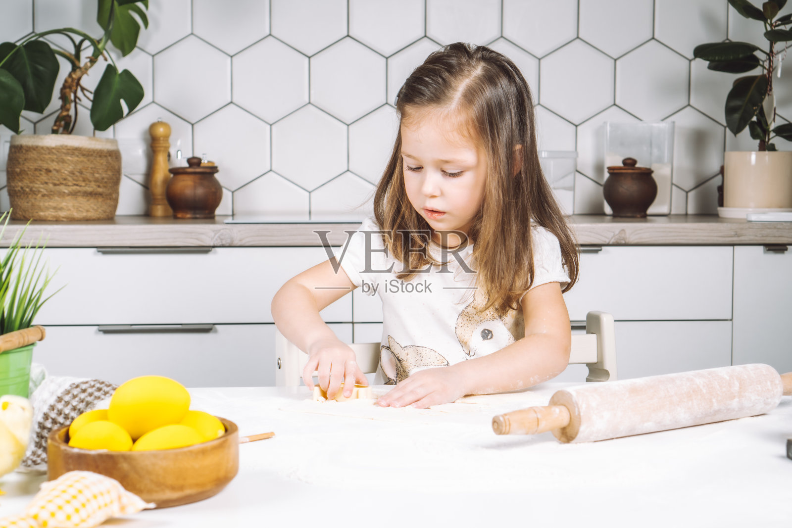 认真的小女孩厨师的肖像，帮助，制作形状面团复活节饼干。造型面团面粉面包杯饼干。照片摄影图片
