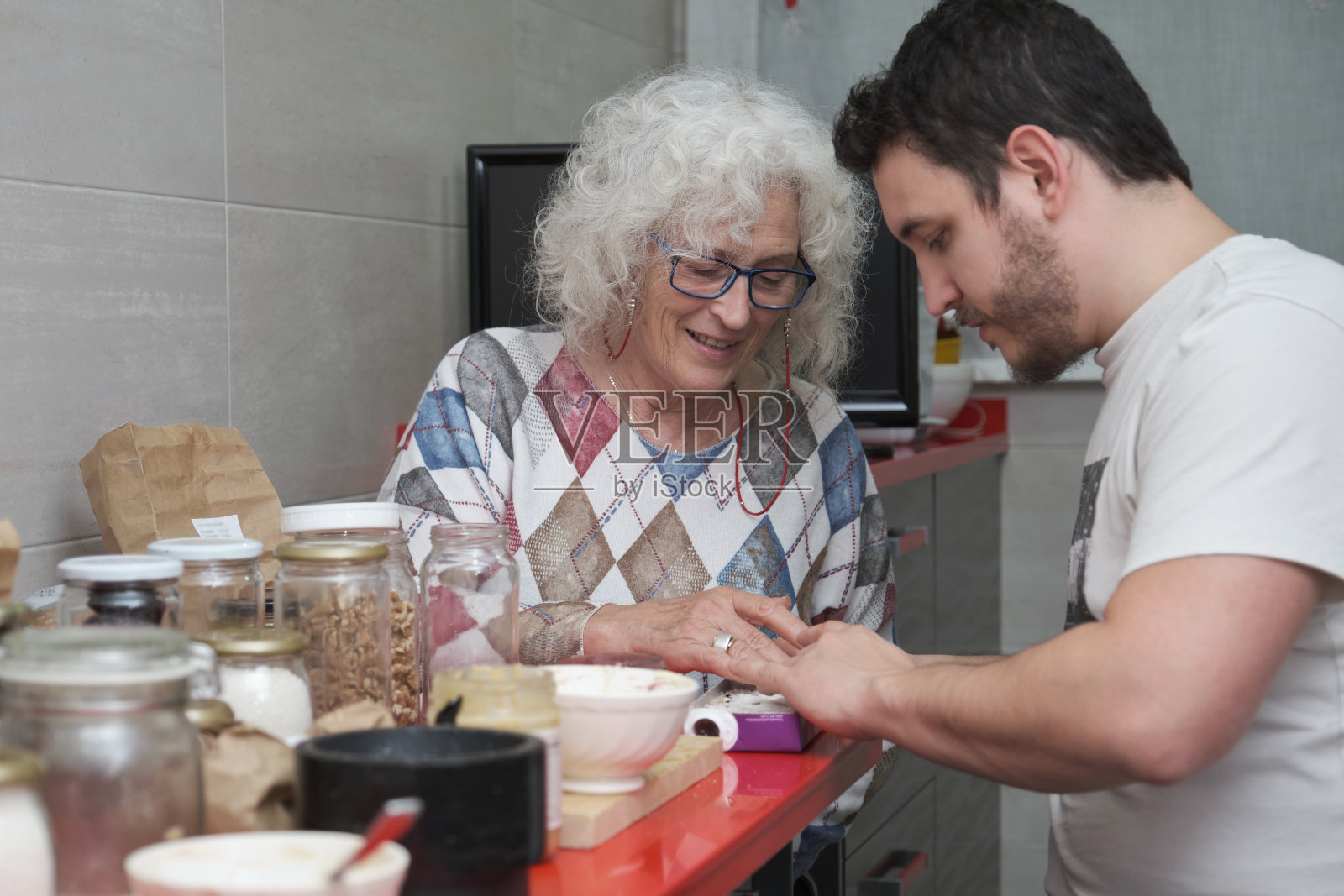 成熟的母亲和成年的儿子一起在厨房准备一些糖果。照片摄影图片