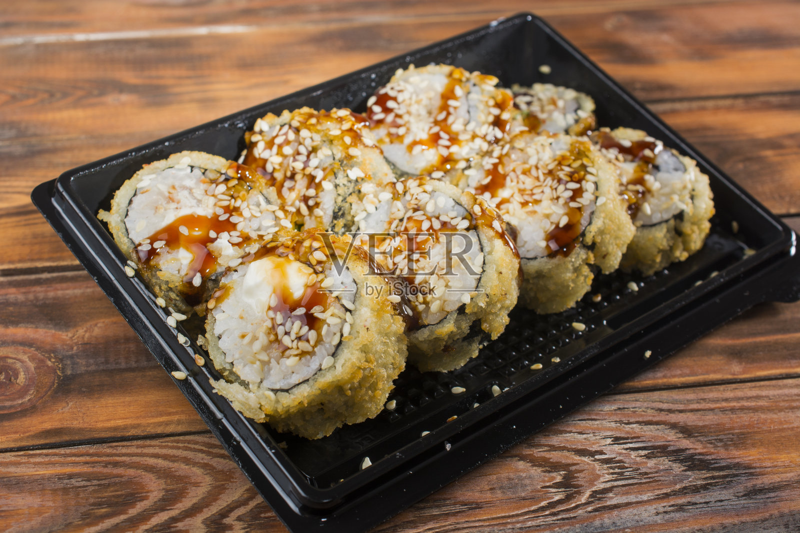 寿司装在黑色塑料容器里，木质背景照片摄影图片