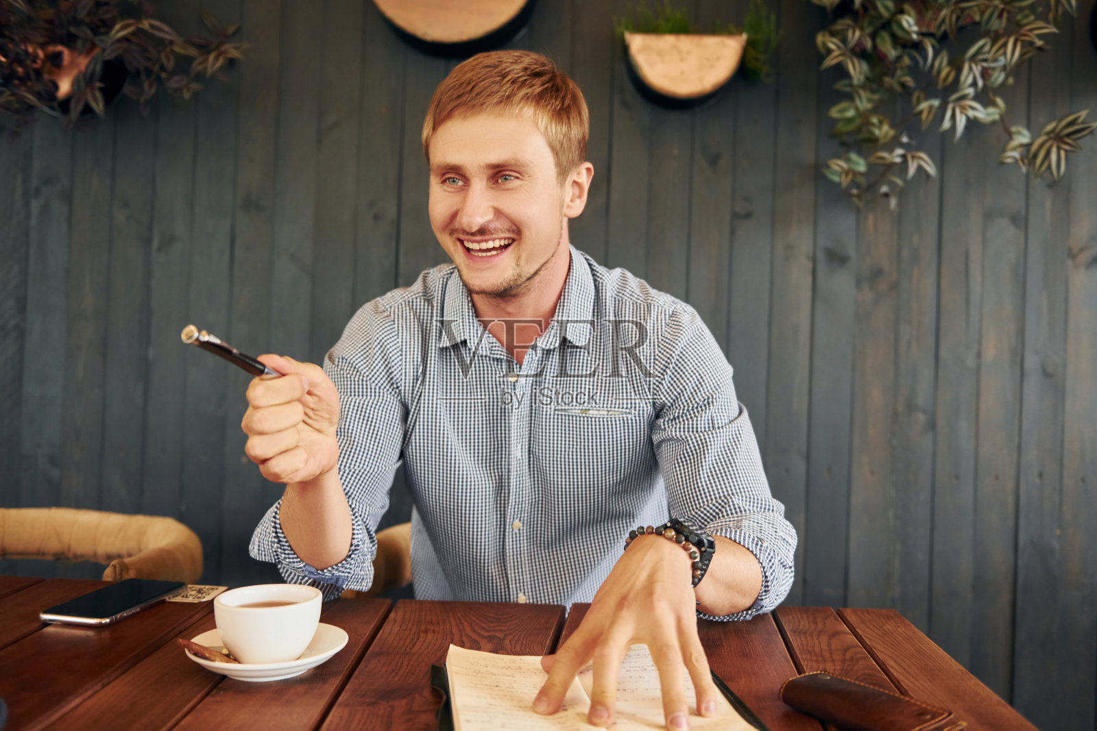 喝杯茶。一个成年男子正坐在室内咖啡馆的桌子旁照片摄影图片