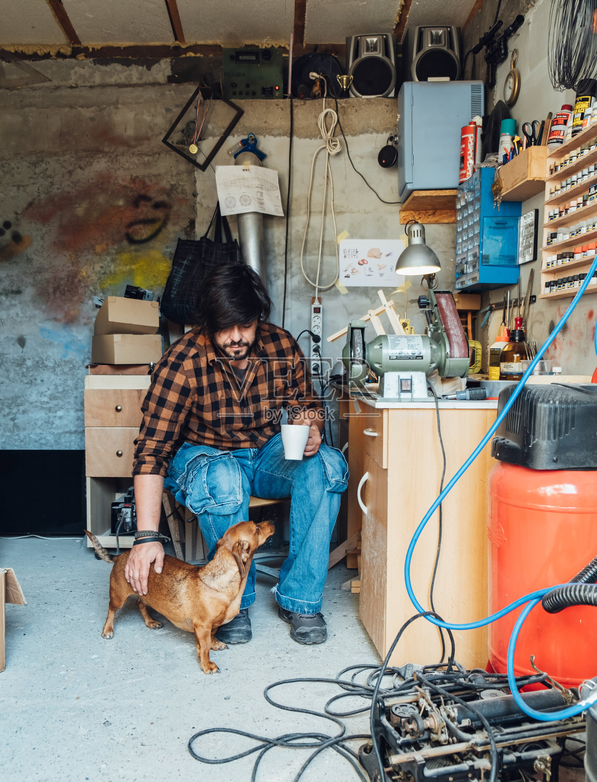英俊的木匠在工作室里抚摸他的狗照片摄影图片