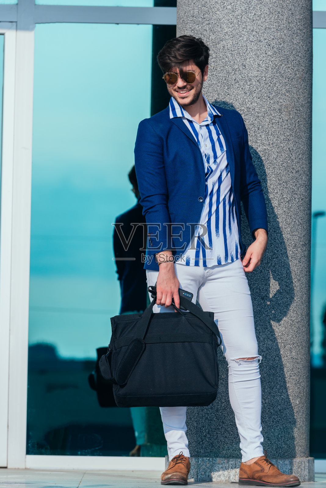 时髦的年轻商人拿着公文包站在办公大楼外照片摄影图片