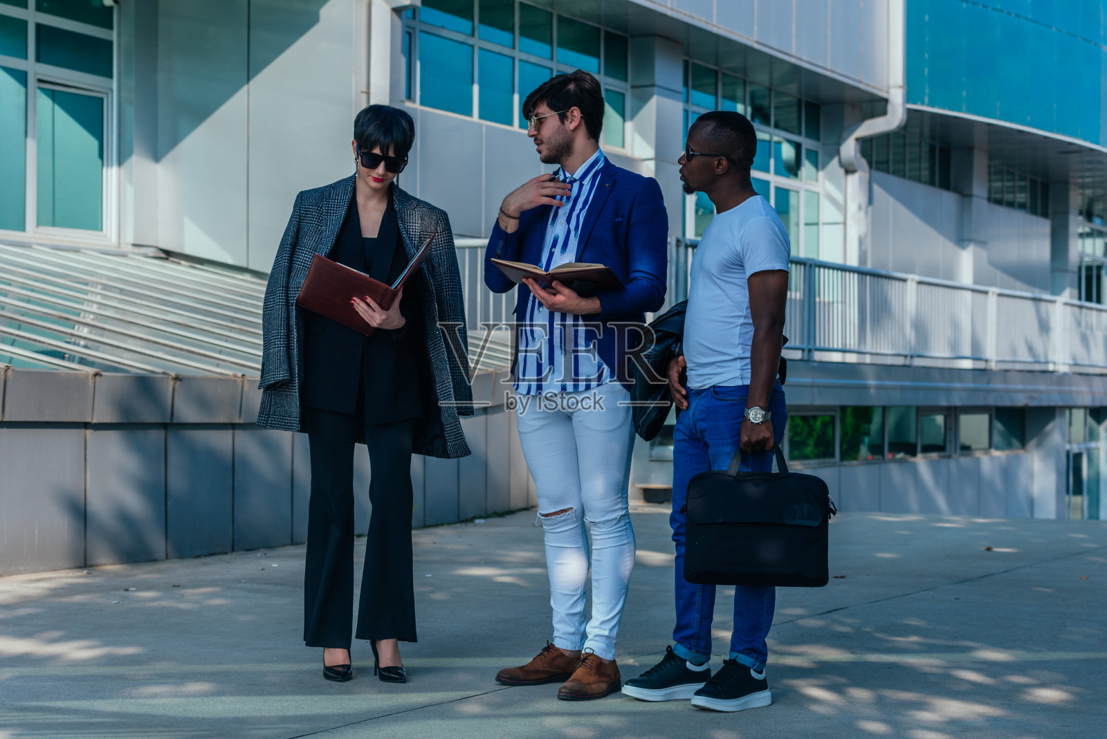 一名商人在他们的现代化办公大楼前向他的多种族同事展示文件照片摄影图片