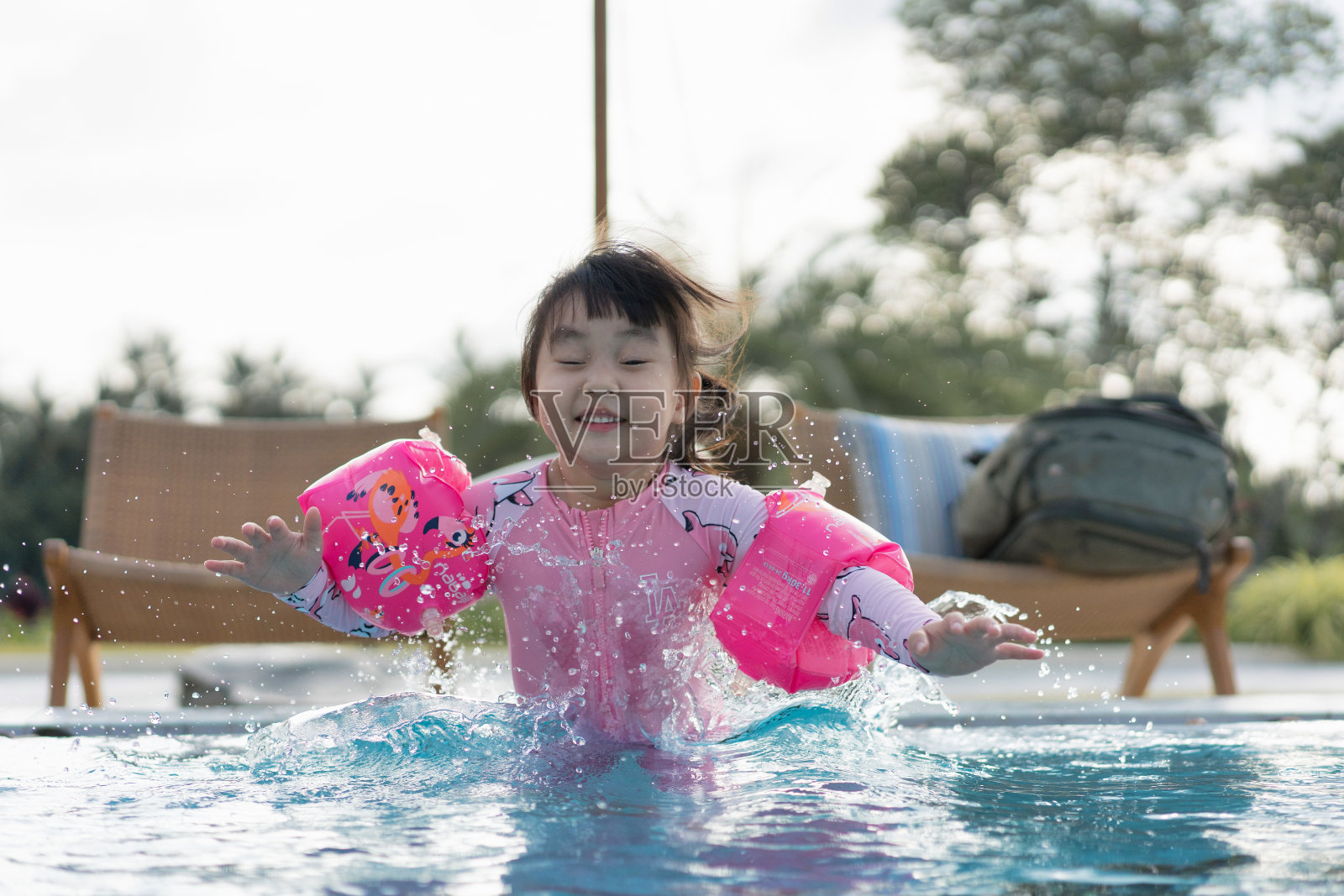 亚洲年轻女孩玩和享受水在游泳池在夏天的一天时间照片摄影图片
