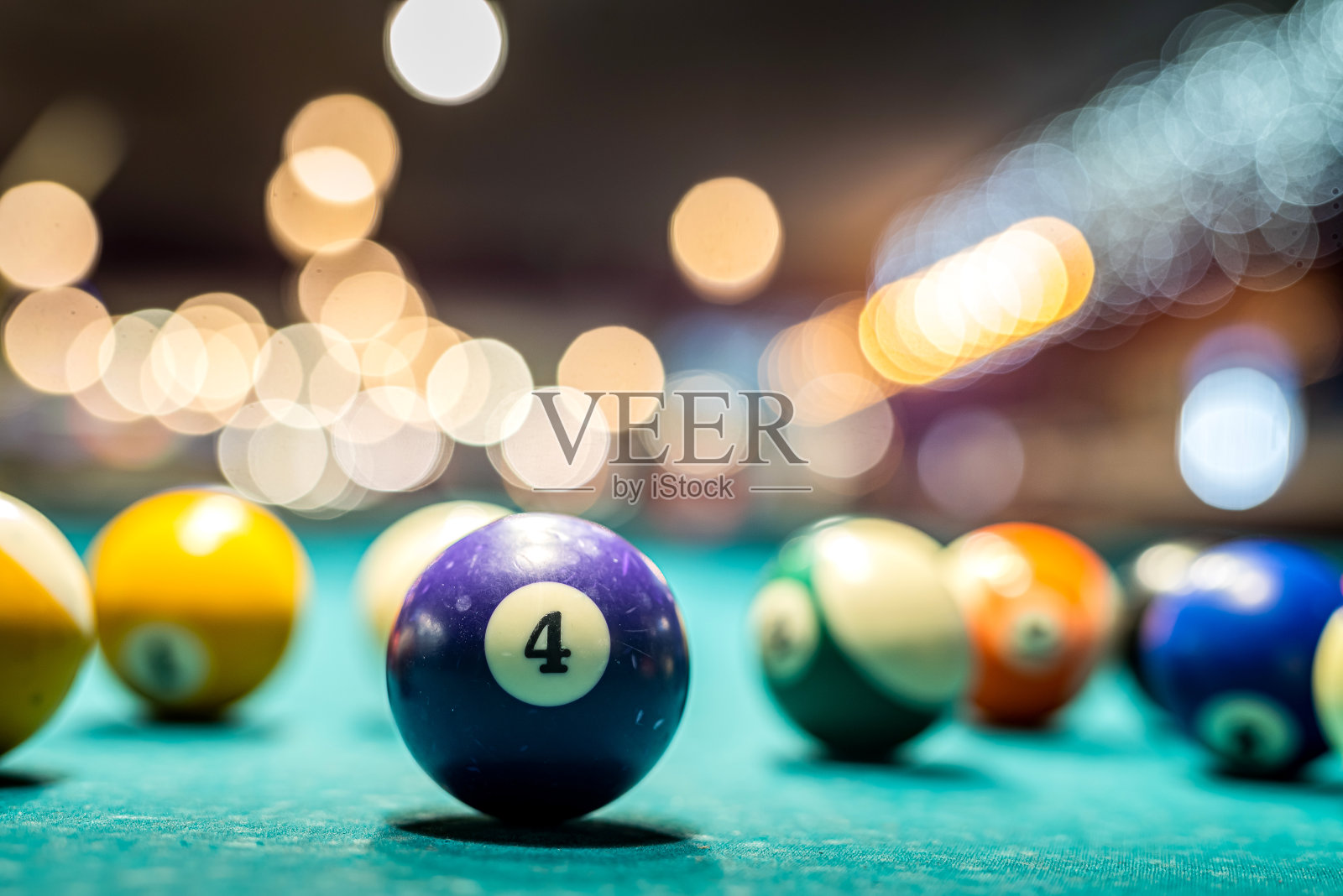 漂亮的彩色数字球躺在台球桌的灯光下。照片摄影图片