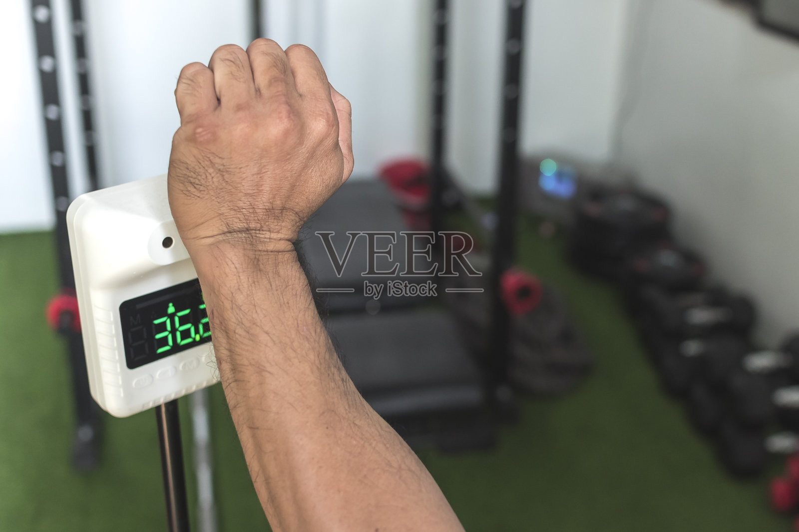 在进入一个小健身房之前，通过手腕上的热扫描仪来测量一个人的体温。照片摄影图片