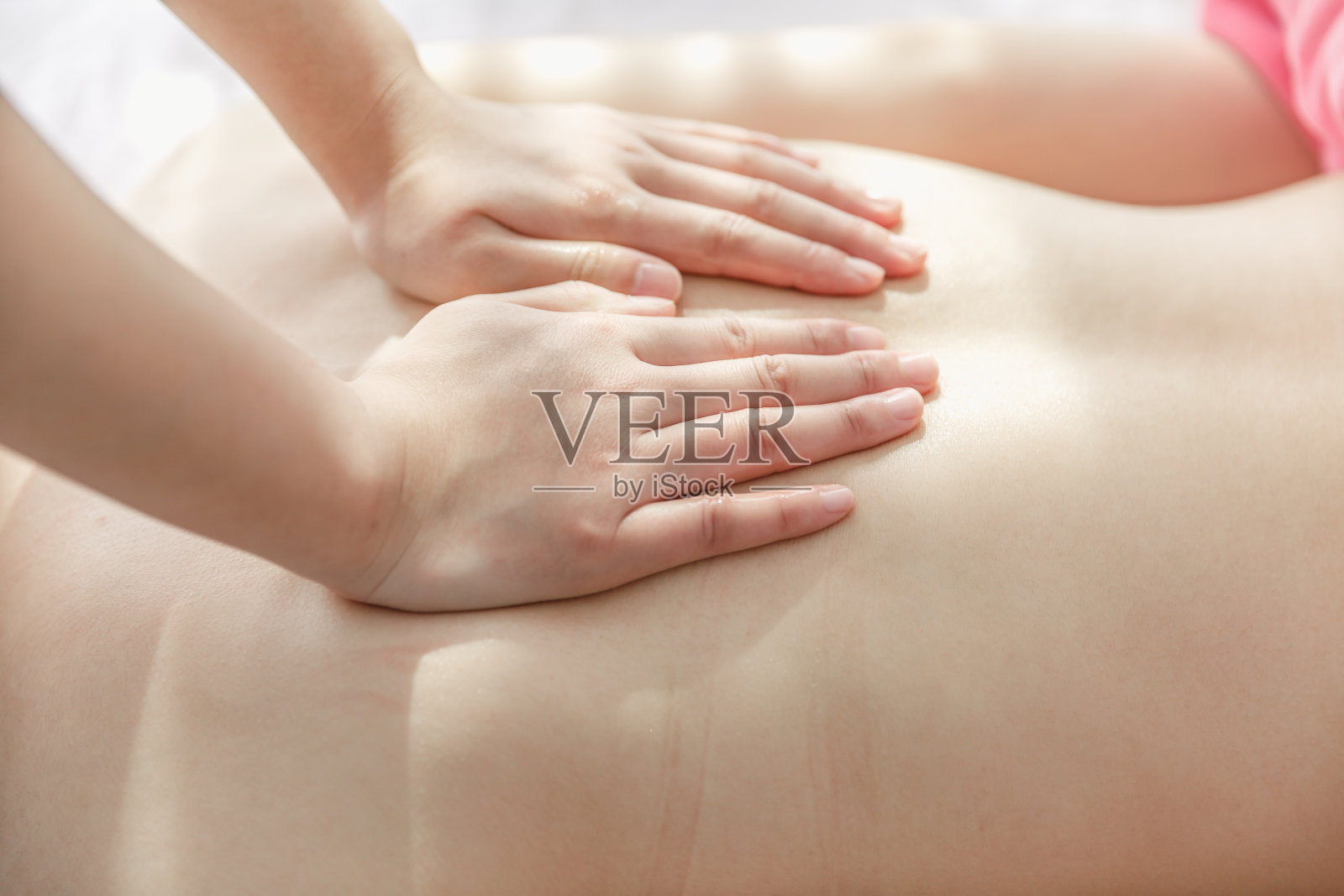 一名年轻女子在水疗中心接受背部按摩。照片摄影图片