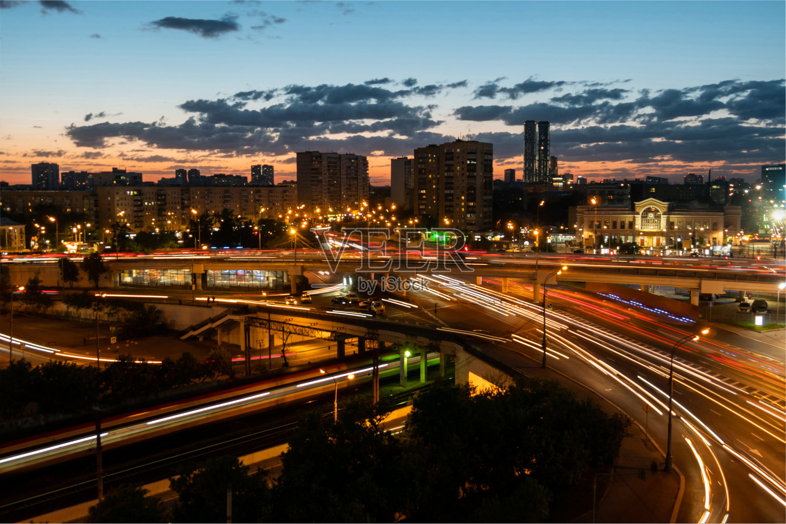 在夜间长时间的暴露下，快速的汽车与小道和温暖的路灯一起行驶照片摄影图片