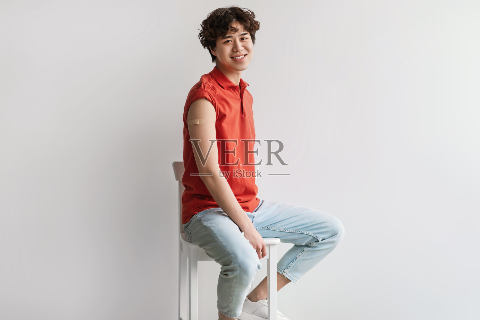 冠状病毒疫苗。年轻的亚洲人在他的手臂上贴着白色背景的胶布，他接种了新冠肺炎疫苗照片摄影图片