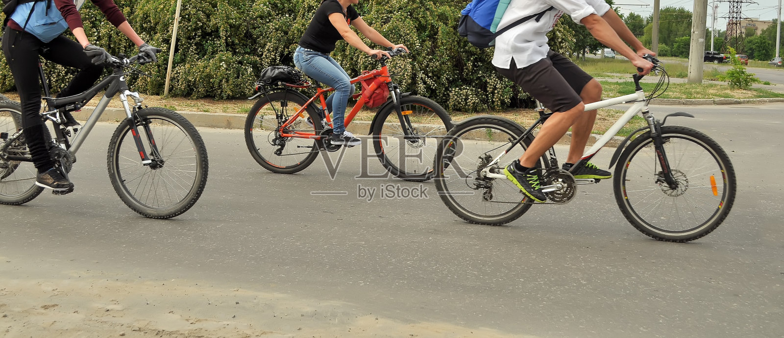 三个没有脸的骑自行车的人在柏油路上，运动模糊。城市里骑自行车，人们穿着休闲照片摄影图片