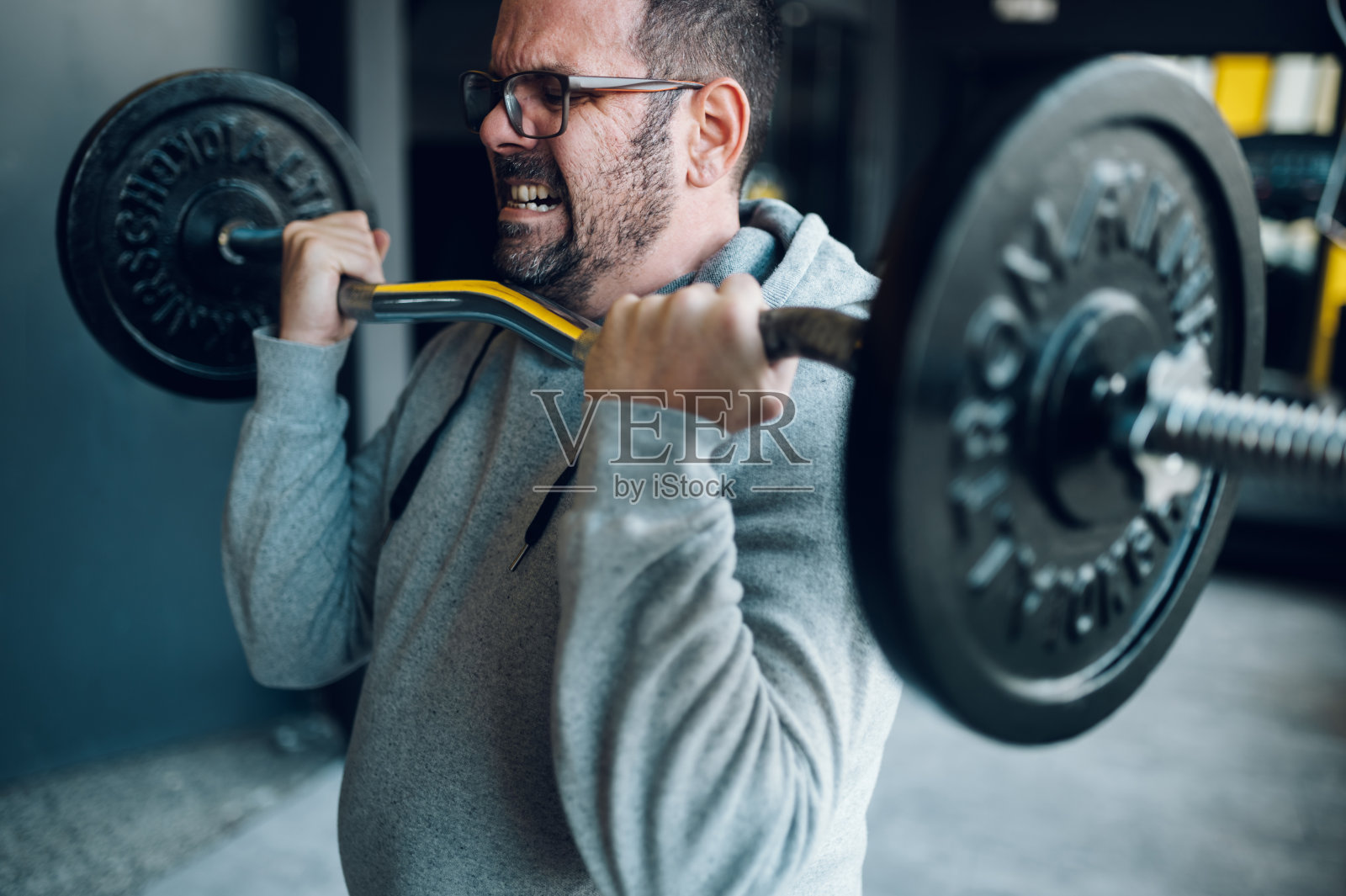 在健身房举杠铃的中年男子照片摄影图片