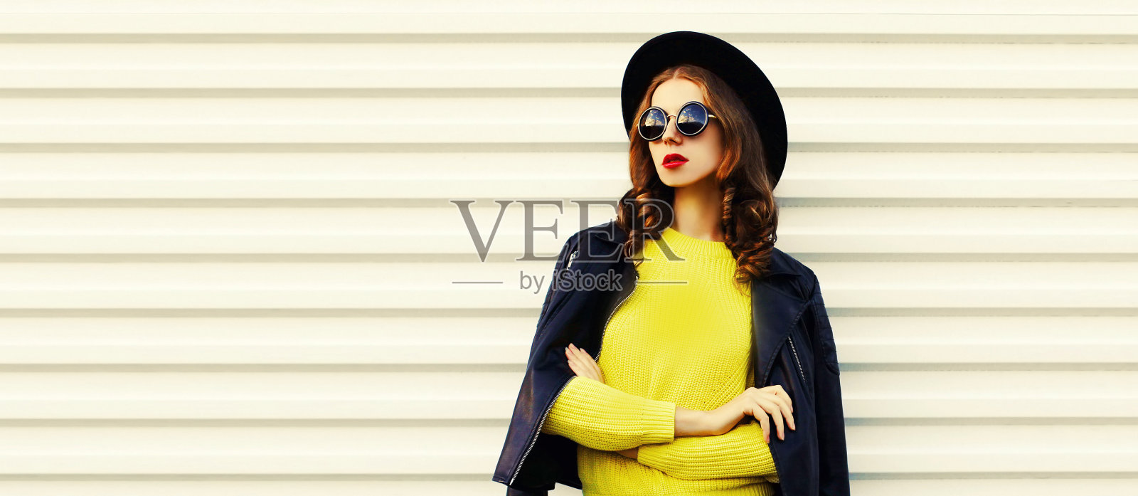 时尚的肖像时尚的女人模特穿着黑色的摇滚风格夹克，黄色的毛衣在白色的背景照片摄影图片