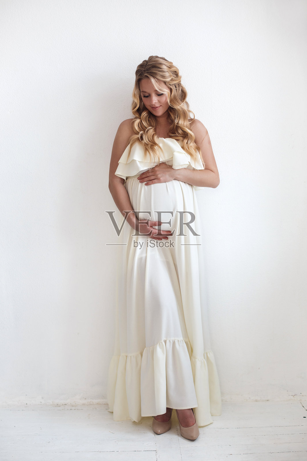 一幅孕妇的肖像，背景为白色，画室里有彩色的大蝴蝶。部分裸露。照片摄影图片