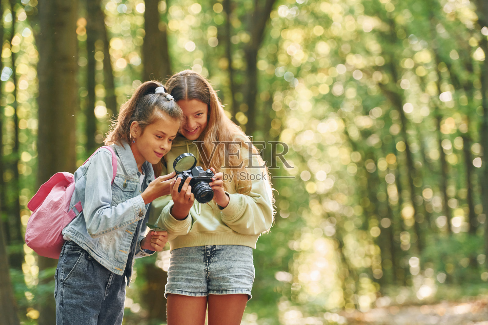 两个朋友。夏天的白天，孩子们一起在绿色的森林里玩耍照片摄影图片