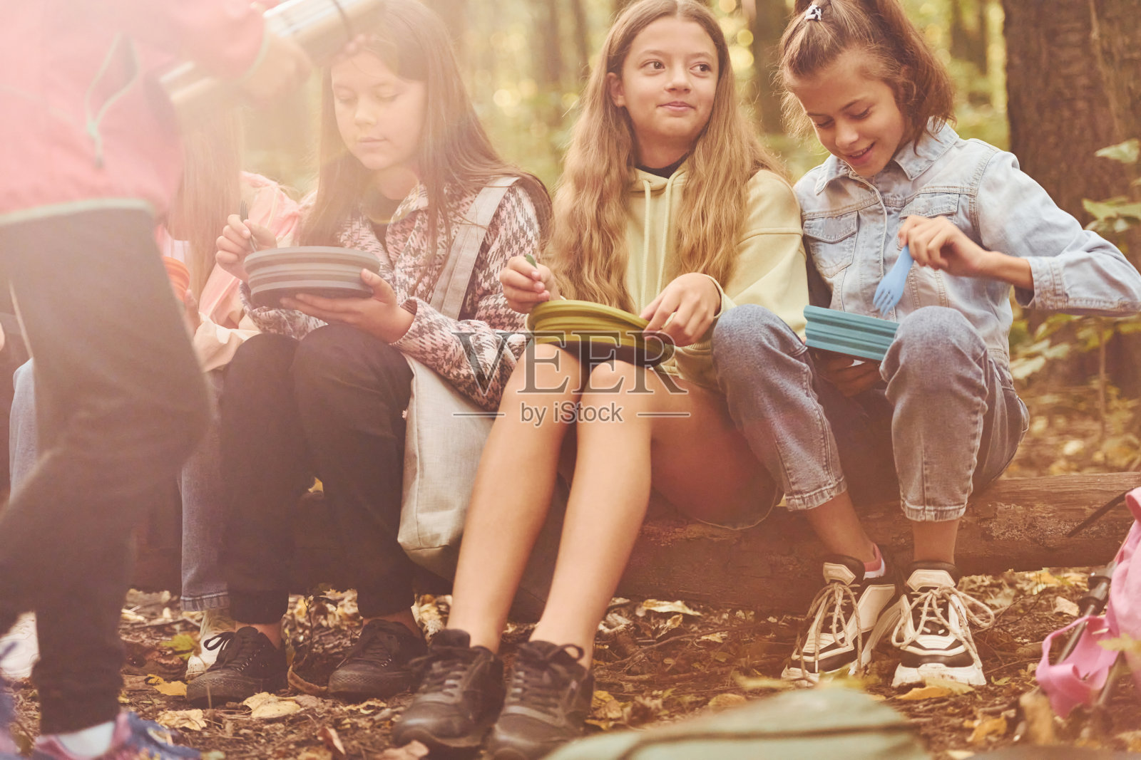 坐着休息一下。夏天的白天，孩子们一起在绿色的森林里玩耍照片摄影图片