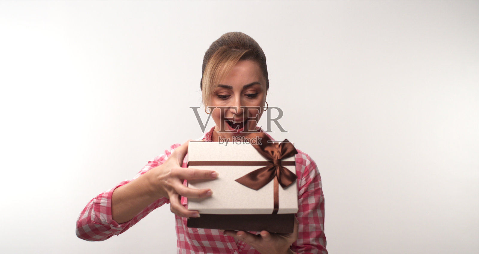年轻女子打开礼品盒，孤立在白色背景的工作室女子。照片摄影图片