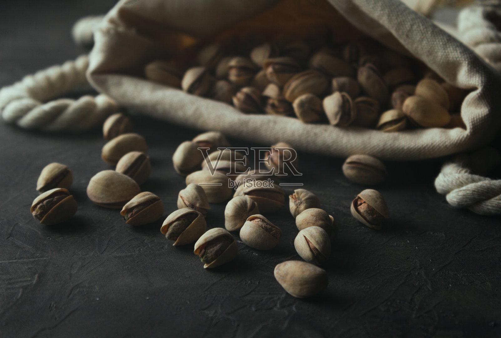 一袋烤开心果和深色背景。照片摄影图片