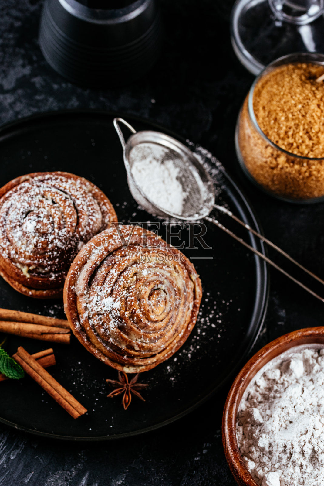 黑色背景的肉桂面包。咖啡、糖、浆果照片摄影图片
